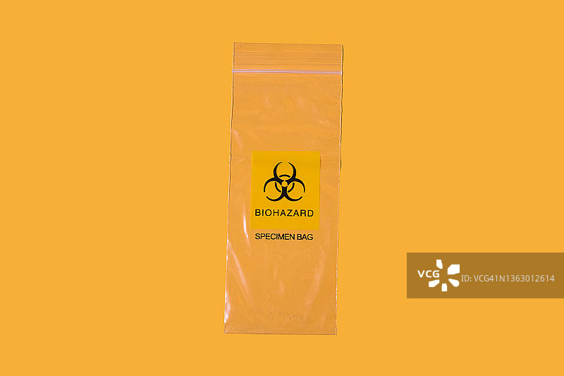 黄色背景上的生物危害标识塑料样本袋：废弃物、污染、新冠病毒概念图片素材