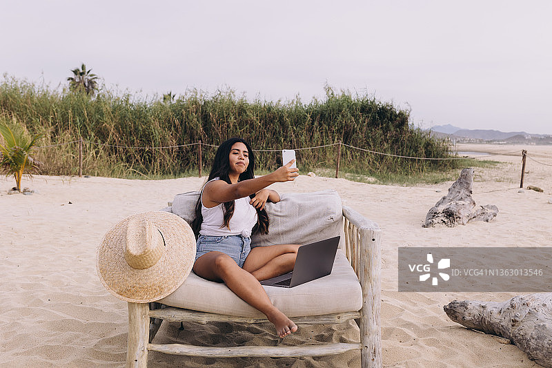 在海滩上自拍的墨西哥女人正面照，头上戴着遮阳帽图片素材