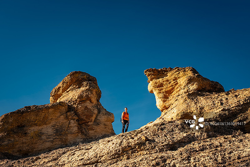 女徒步者走过俄勒冈沙漠中荒凉的岩石景观图片素材