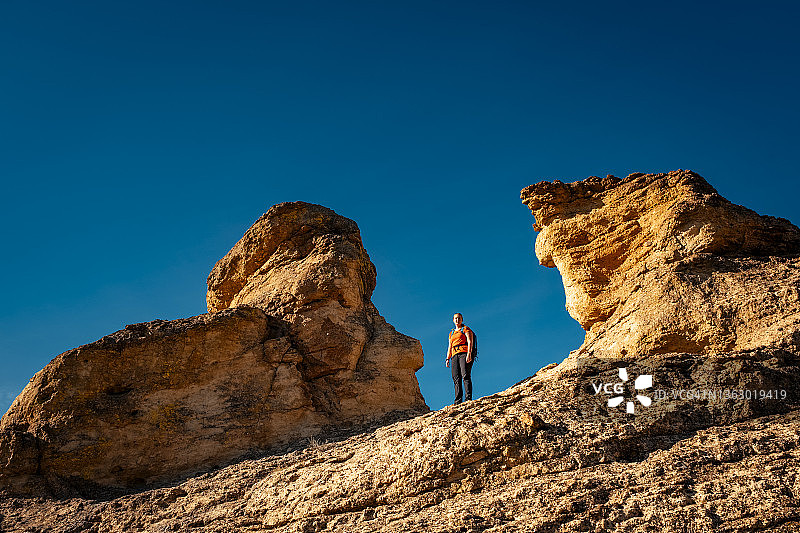 女徒步者站在俄勒冈州史密斯岩沙漠地区的两座岩石塔之间图片素材