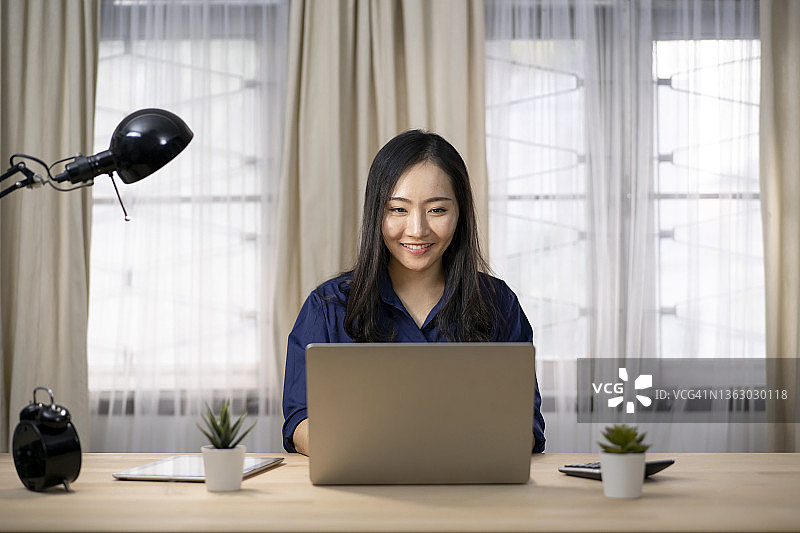 在家用笔记本电脑工作的微笑女商人图片素材