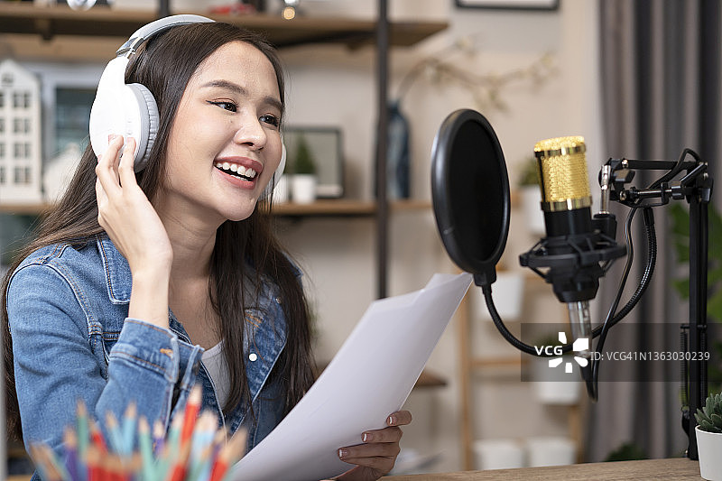 女博主在工作室用笔记本电脑、耳机和专业麦克风录制在线播客图片素材