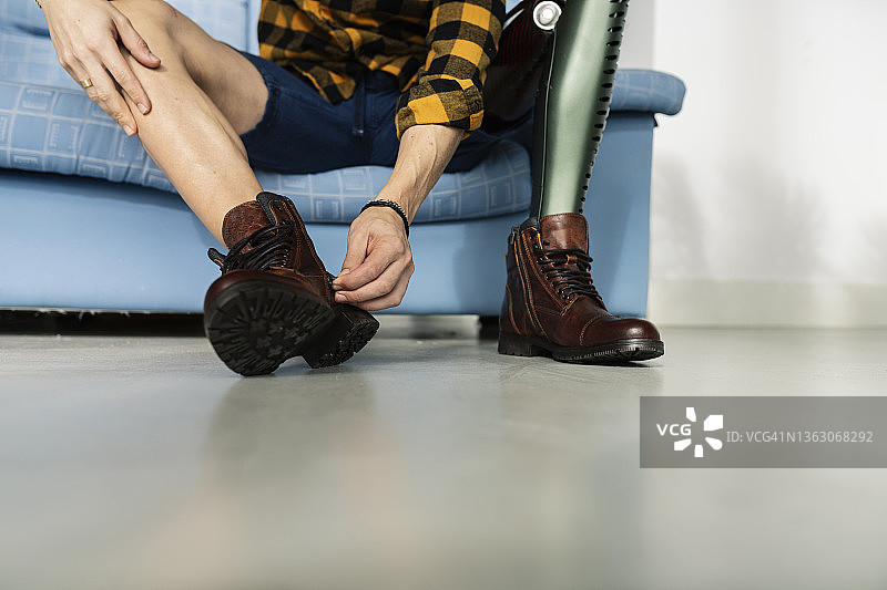用腿部假肢的男人系鞋带图片素材