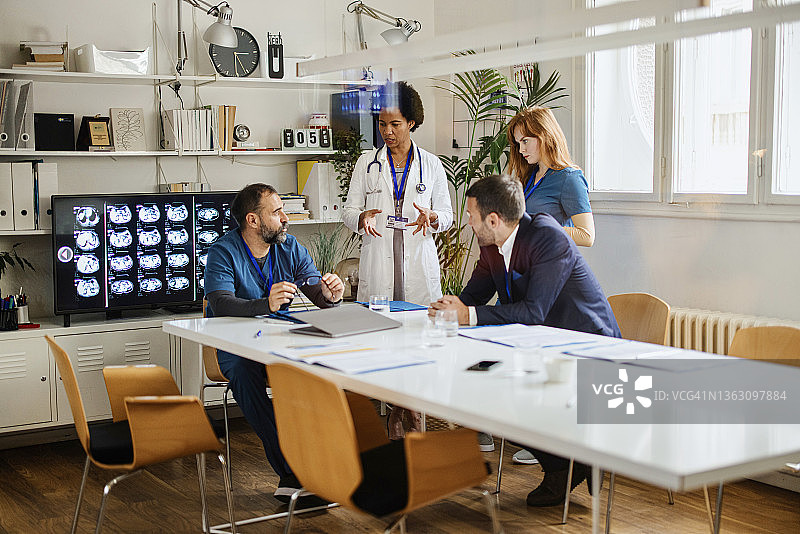中年医生在会议期间与他的医疗人员讨论事情图片素材