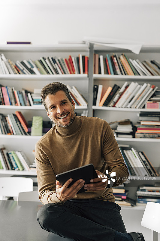 在图书馆使用平板电脑备课的年轻帅气男教师图片素材