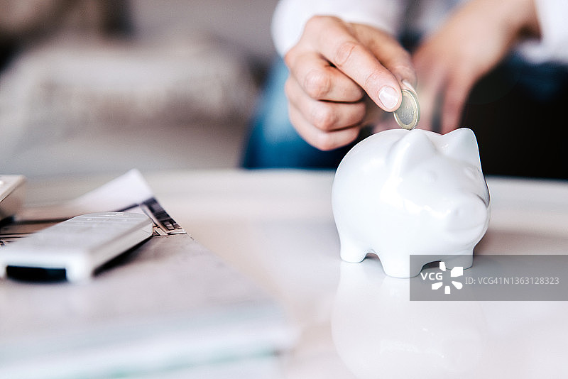 女人往储蓄罐里放硬币图片素材