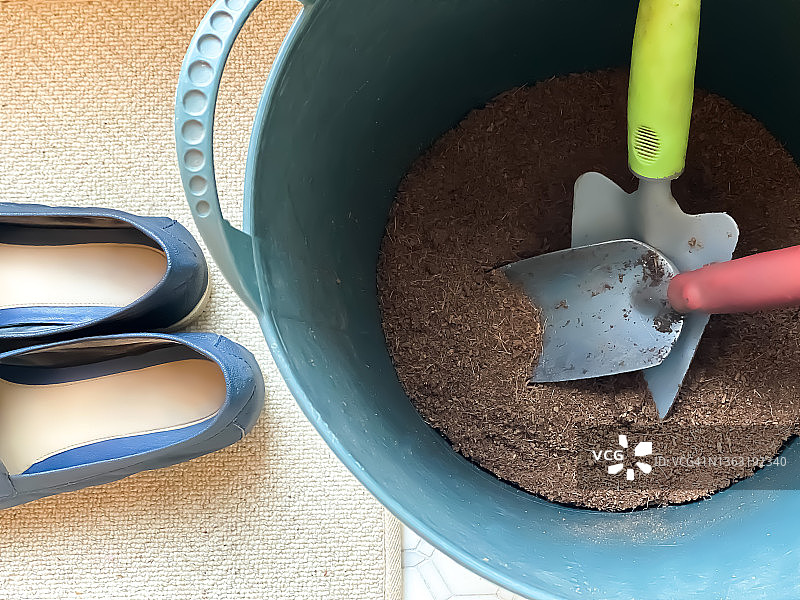 橡胶园艺桶与起始土壤和泥铲旁的门垫和鞋子图片素材