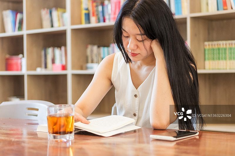 在图书馆课桌前阅读的年轻女性图片素材