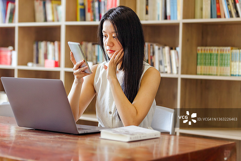 在图书馆使用手机的年轻女性图片素材
