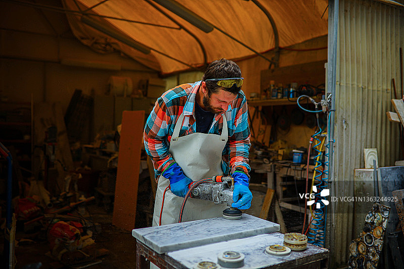 在他的工作室里，专注而敬业的石匠使用砂光/抛光机加工大理石图片素材