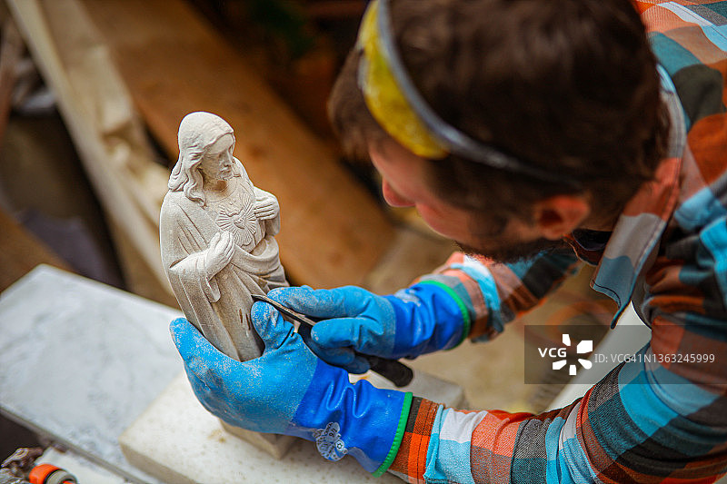 男雕塑家在工作室雕刻小型雕像图片素材
