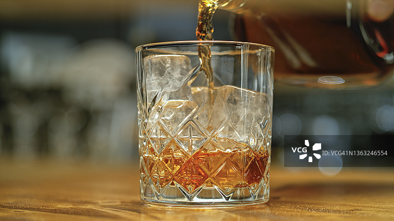 将威士忌倒入装有冰块的玻璃杯中图片素材