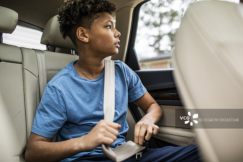 坐在汽车后座，望向窗外的少年图片素材