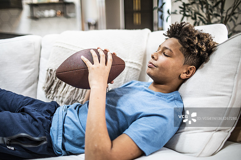 少年在家拿着足球，正在做白日梦图片素材