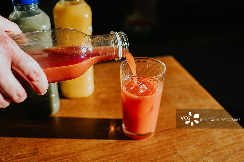 手持果汁瓶并将果汁倒入玻璃杯中图片素材
