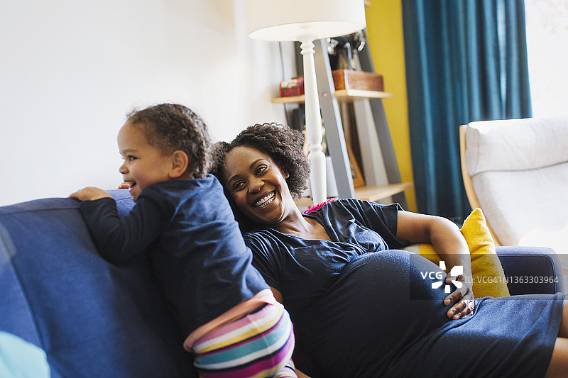 在沙发上嬉戏的孕妇和女儿图片素材