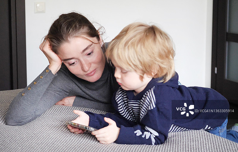 漂亮妈妈和儿子在床上玩手机图片素材