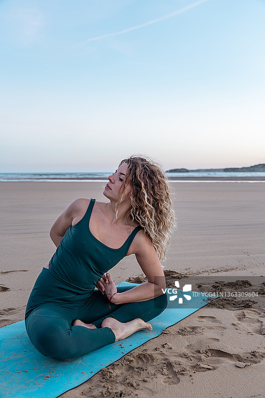 在海滩上做瑜伽的漂亮金发女子图片素材