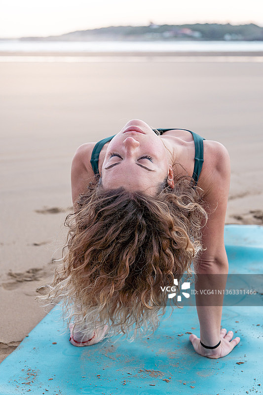 在海滩上做瑜伽的漂亮金发女子图片素材