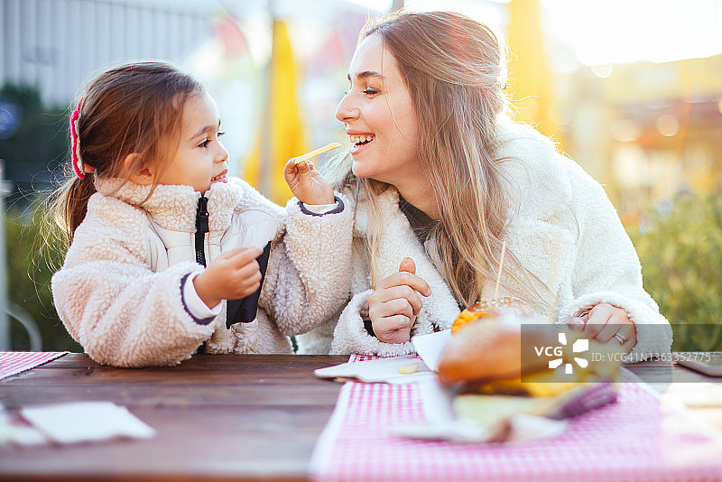 在快餐店吃汉堡和热狗的母女图片素材