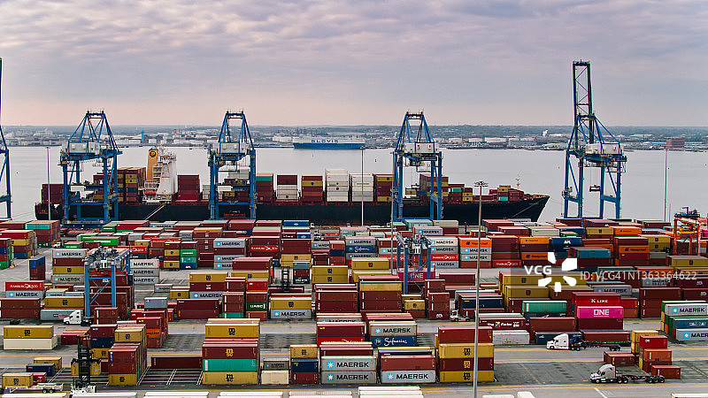 卡车在巴尔的摩港运输集装箱，起重机卸船 - 航拍图片素材