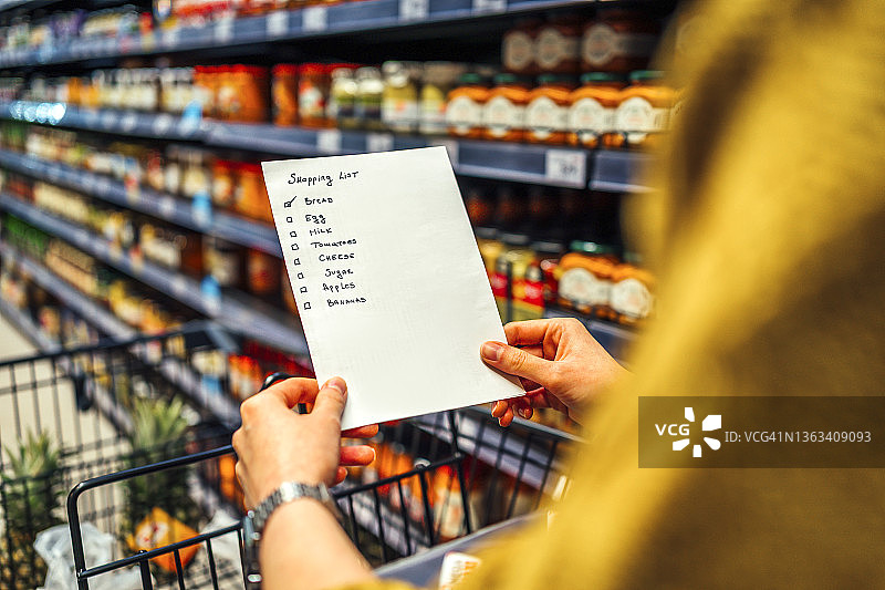 拿着购物清单的女人在杂货店图片素材