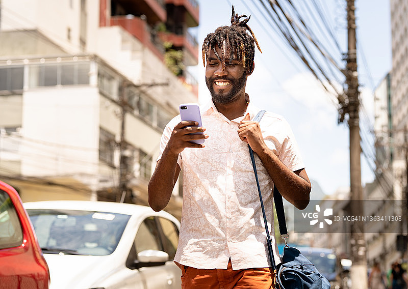 走在街上用手机的时尚年轻男人图片素材