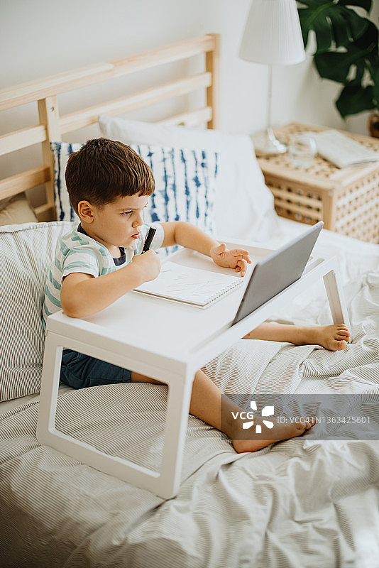 幼儿坐在床上学习写字图片素材