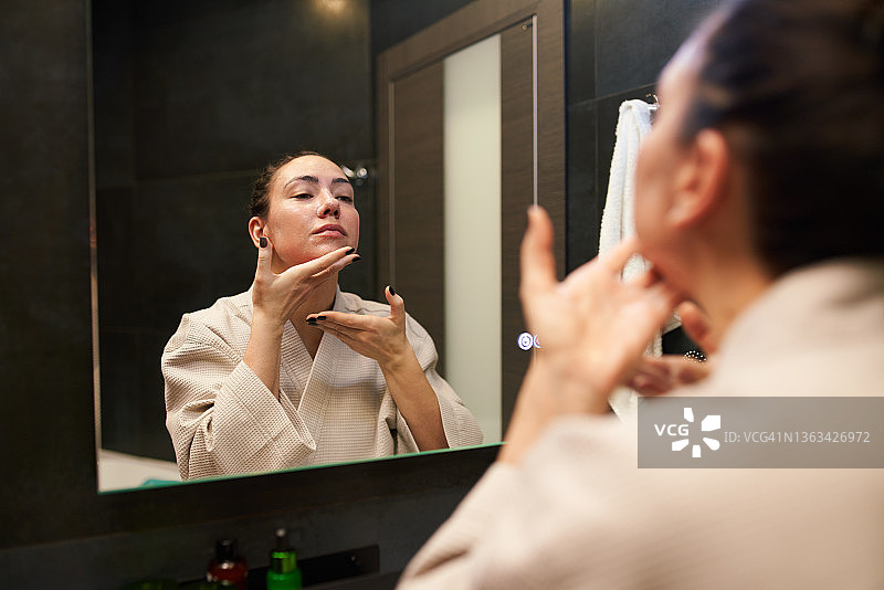 在镜子前按摩面部的女人图片素材