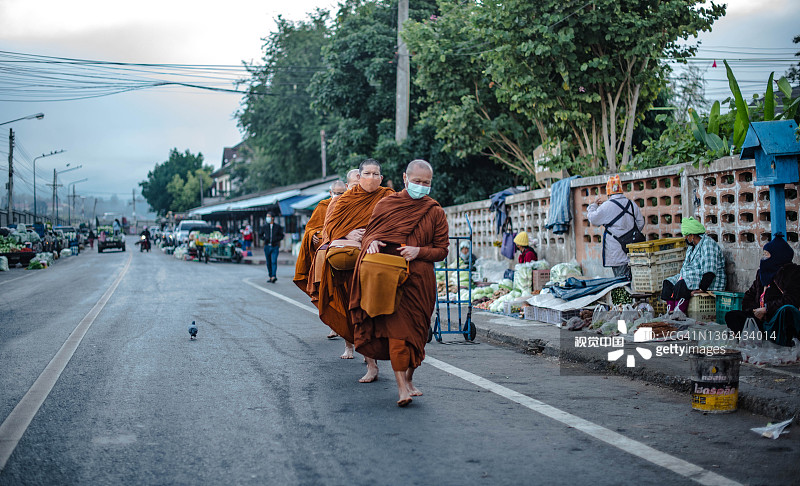 在夜丰颂府，僧侣出来接受施舍时必须戴口罩，以防止感染COVID-19图片素材