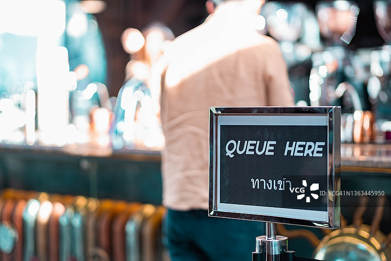 咖啡店保持社交距离的“在此排队”地面贴纸图片素材