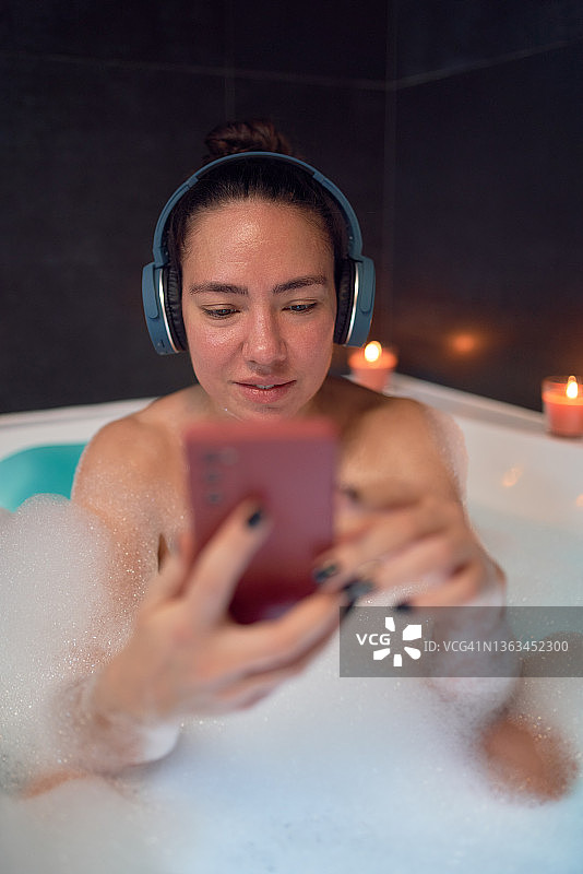 女人在浴缸里浏览智能手机图片素材