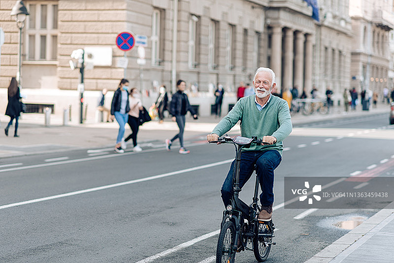 年长的男人骑自行车穿梭于城市中图片素材