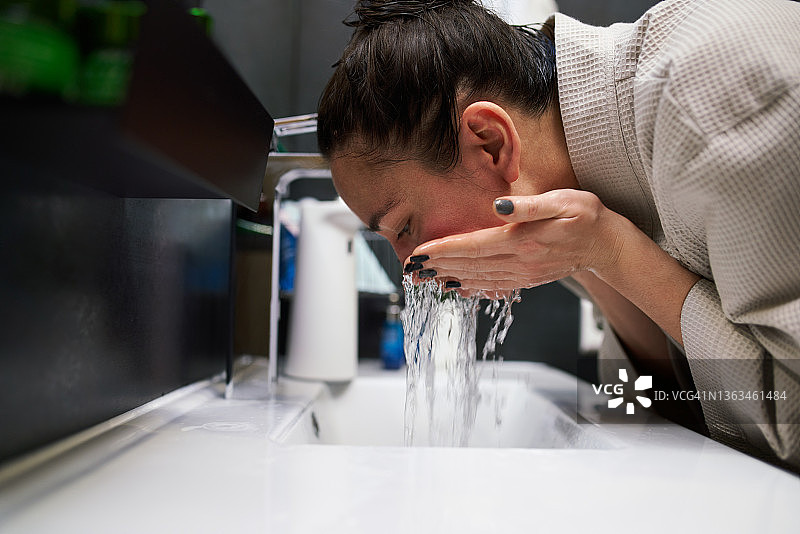 女人在水槽上洗脸图片素材