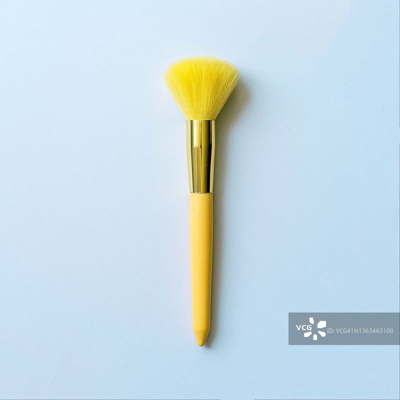 灰色蓝色背景上带人造黄色鬃毛的化妆刷套装图片素材