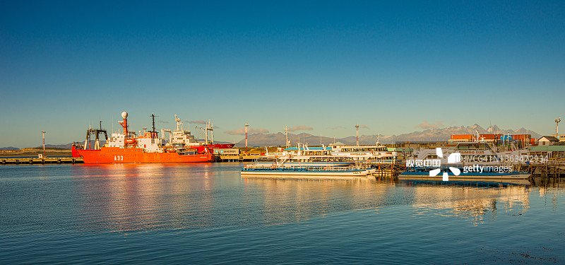 阿根廷巴塔哥尼亚火地岛国家公园乌斯怀亚港口的货轮和游轮，金色秋季日落时分图片素材