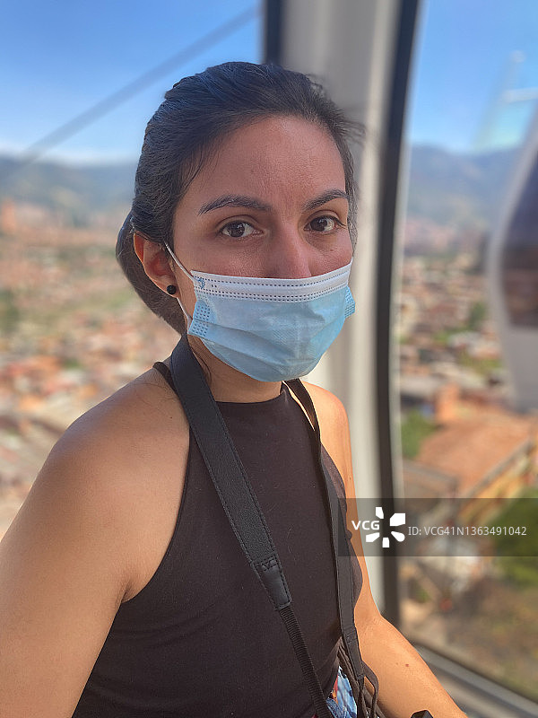 棕发秘鲁女性乘坐缆车，背景是晴朗美丽麦德林城市景观图片素材
