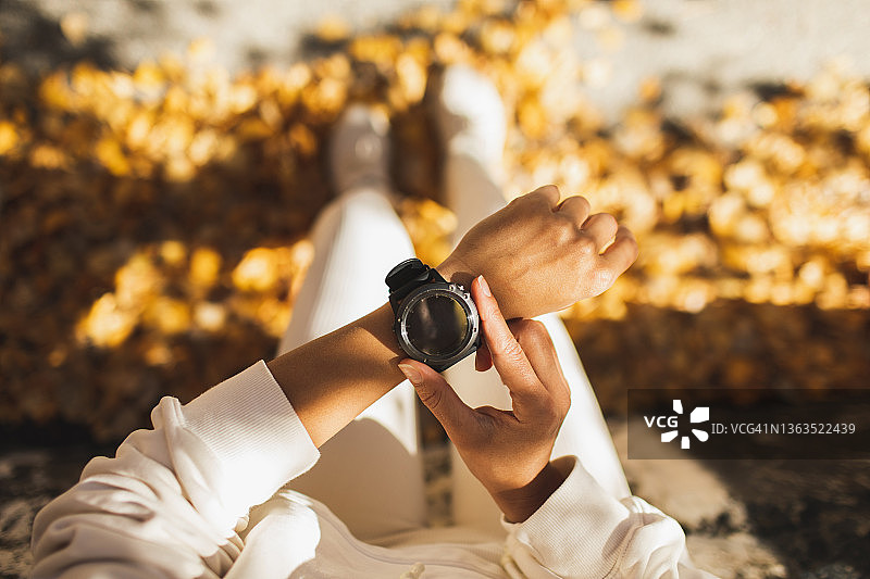 女人在户外跑步训练前使用健身追踪器或智能手表。特写照片，带复制空间图片素材