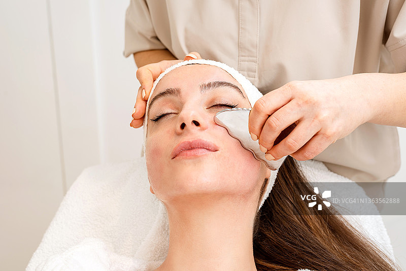 美女在美容院接受面部提拉按摩图片素材