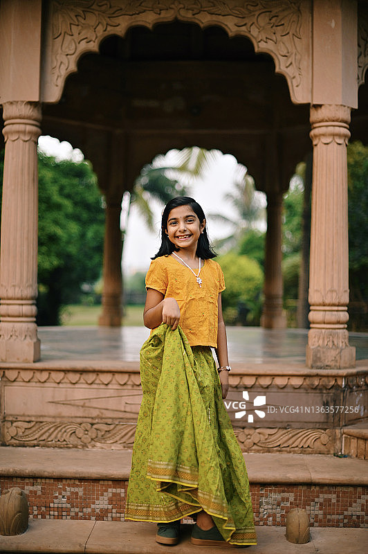 穿着印度传统服装，站在建筑柱子前的可爱女孩图片素材