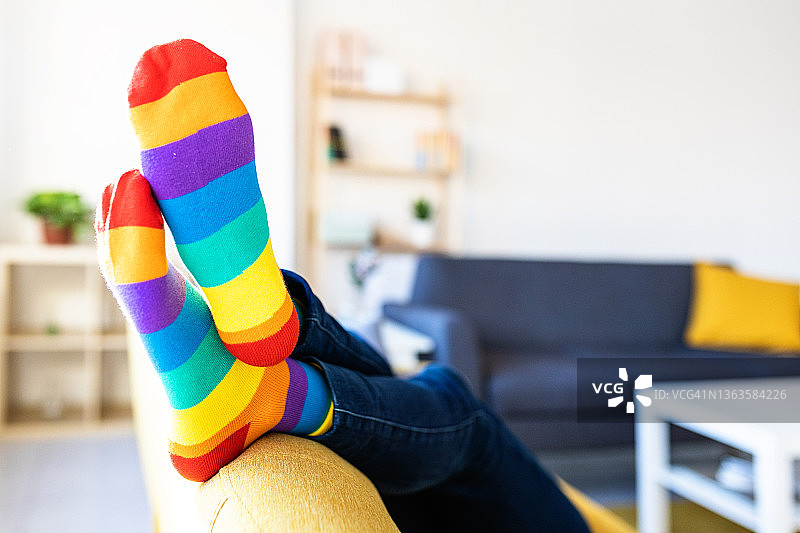 穿着彩色条纹袜子的女人在家里的沙发上放松图片素材