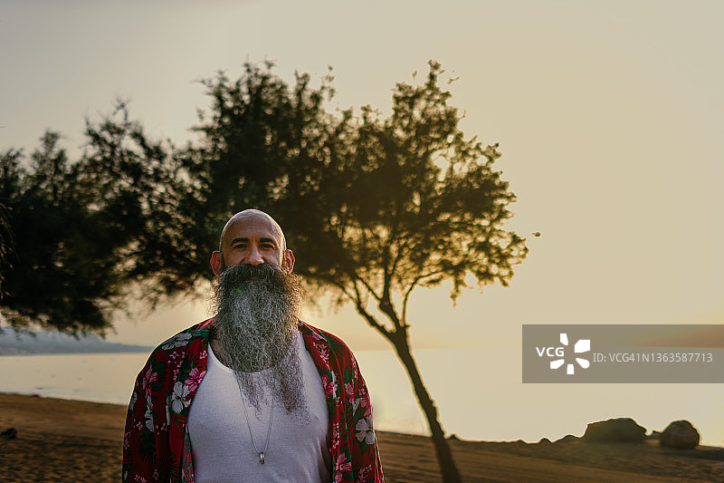 夏威夷海滩日出时分的光头胡须男图片素材