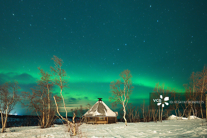 冬季极夜期间，瑞典拉普兰阿比斯库传统圆锥形帐篷上的北极光图片素材