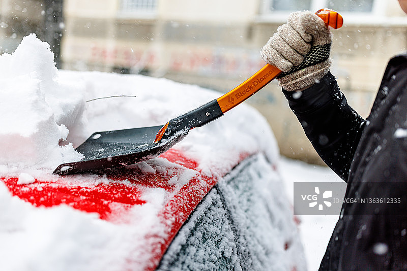 男人用雪铲清理汽车上的积雪图片素材