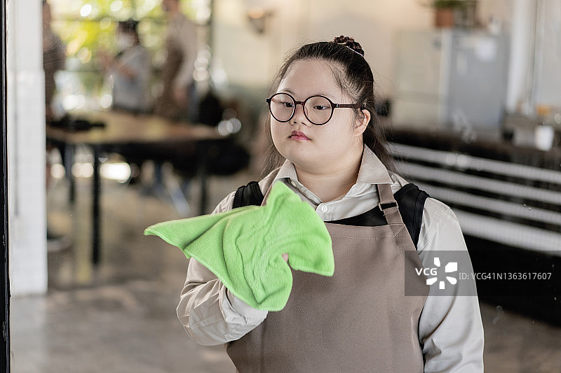 患唐氏综合征的女服务员清洁咖啡馆的窗户图片素材