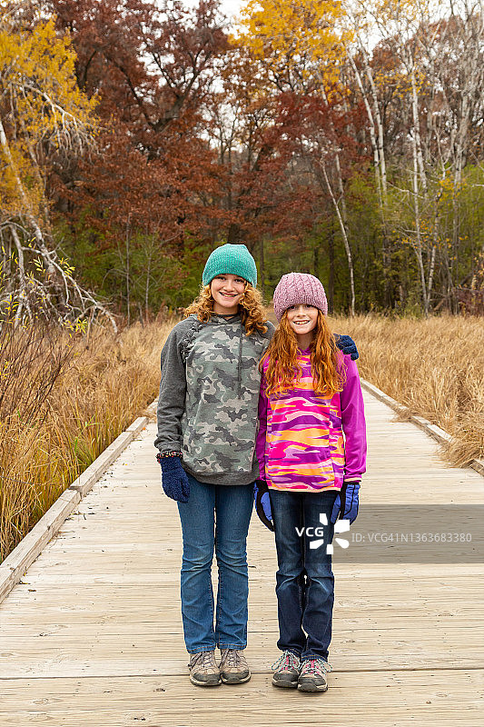 秋季站在浮动木桥上的两个女孩图片素材