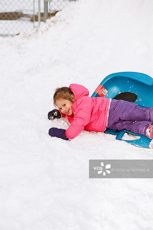 小女孩雪地玩雪橇摔倒笑，纽约布法罗图片素材