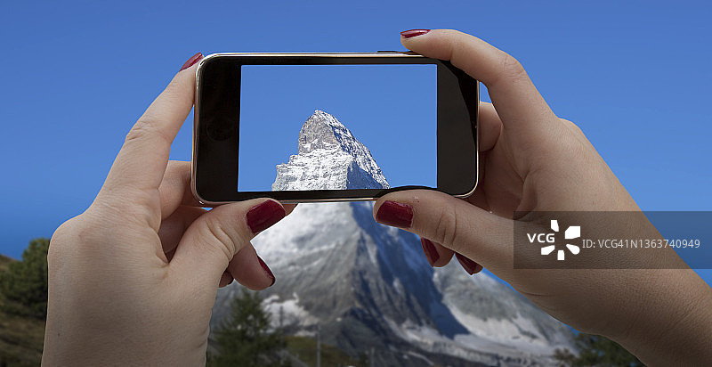 用智能手机拍摄马特洪峰的女人图片素材