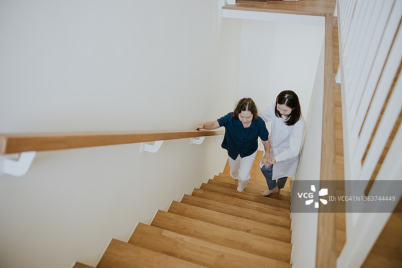 医生搀扶母亲上楼梯照片图片素材