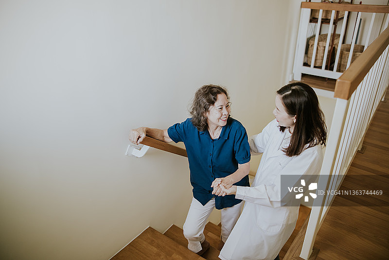 女医生帮助老年妇女在家上楼梯图片素材